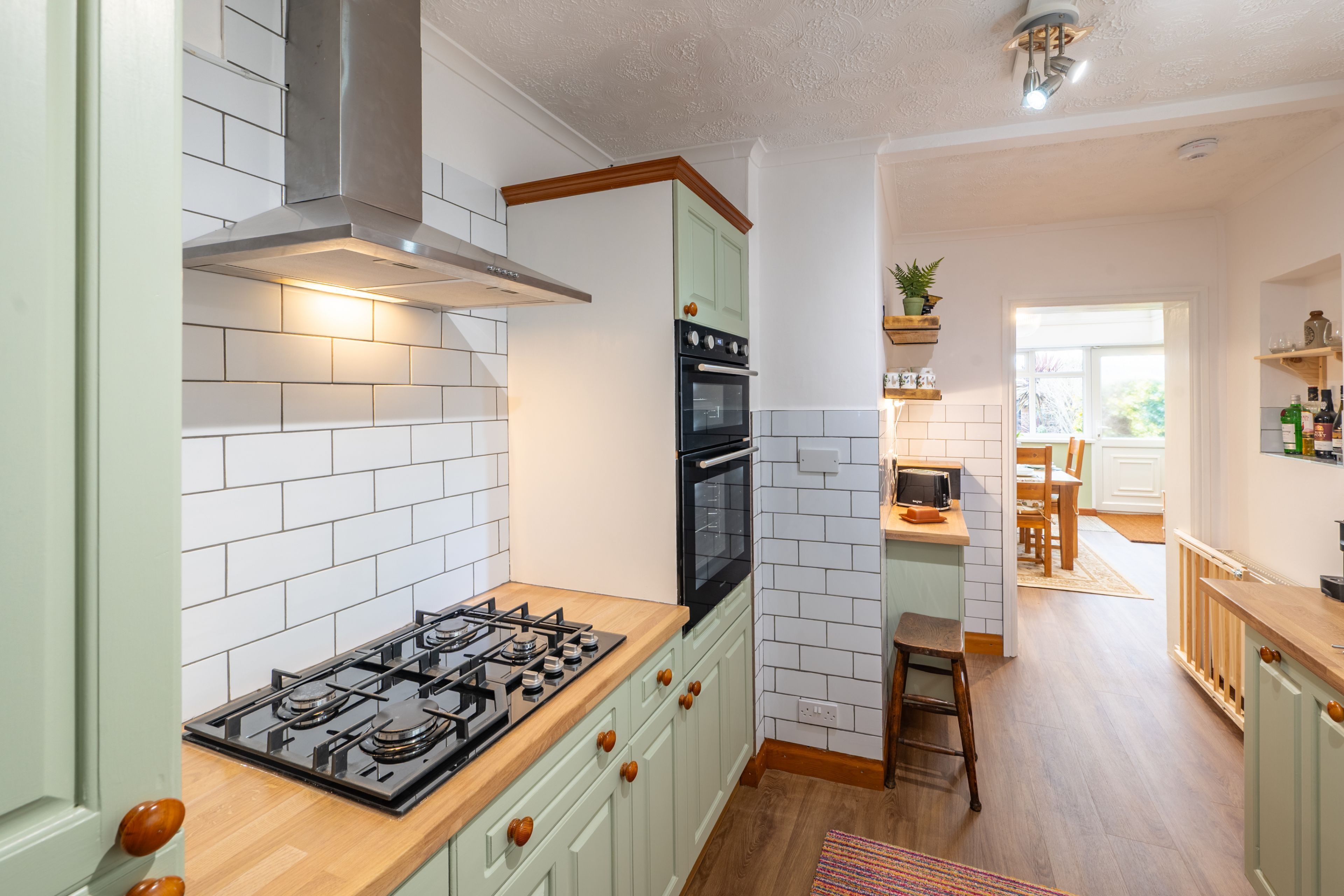 Una cocina con paredes de azulejos blancos, estufa, horno y armarios de madera.
