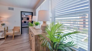 A modern living room with a wooden floor, a sofa, a coffee table, and a large window with blinds.