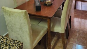 A dining area with a wooden table, cushioned chairs, a remote control, and a flower vase. - Seaside Apartment in Vera With Terrace (Vera)