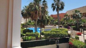 A pool area with palm trees, a clear blue sky, and a building in the background. - Seaside Apartment in Vera With Terrace (Vera)