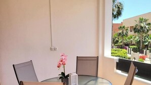 A round glass table with four chairs, a potted plant, and a small white object on the table. - Seaside Apartment in Vera With Terrace (Vera)