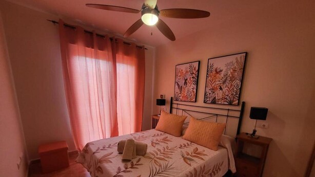 A bedroom with a bed, curtains, a ceiling fan, two wall-mounted lamps, and two framed artworks. - Seaside Apartment in Vera With Terrace (Vera)