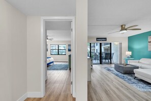 A modern living room with a white sofa, a coffee table, and a ceiling fan. - Quick Walk To Beach- Large Pool with Deck- Golden Shores 210 (Indian Shores)