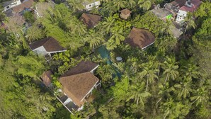 Oversigtsbillede af et boligområde med huse omgivet af frodig beplantning og en central swimmingpool.