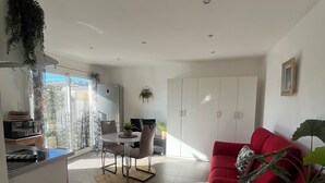 A modern living space with a red sofa, a dining area, and a kitchen. - Le Chic Azuréen (Villeneuve-Loubet)