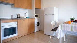 A compact kitchen with wooden cabinets, a washing machine, a microwave, and a refrigerator. - Vacation Apartment in Roquetas de Mar (Roquetas de Mar)
