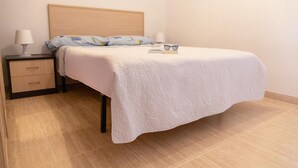 A neatly made bed with a white quilt, a bedside lamp, and a book on the nightstand. - Vacation Apartment in Roquetas de Mar (Roquetas de Mar)