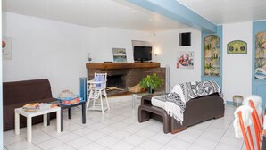 Ein Wohnzimmer mit einer Couch, einem Couchtisch, einem Fernseher, einem Kamin und einem Babyschaukelstuhl.
