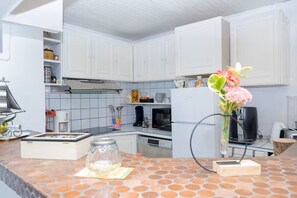 Una cocina moderna con armarios blancos, salpicadero de azulejos y encimera con un jarrón de flores.