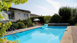 Ein Schwimmbecken mit klarem, blauem Wasser, umgeben von einem mit Kieselsteinen belegten Beckenrand.