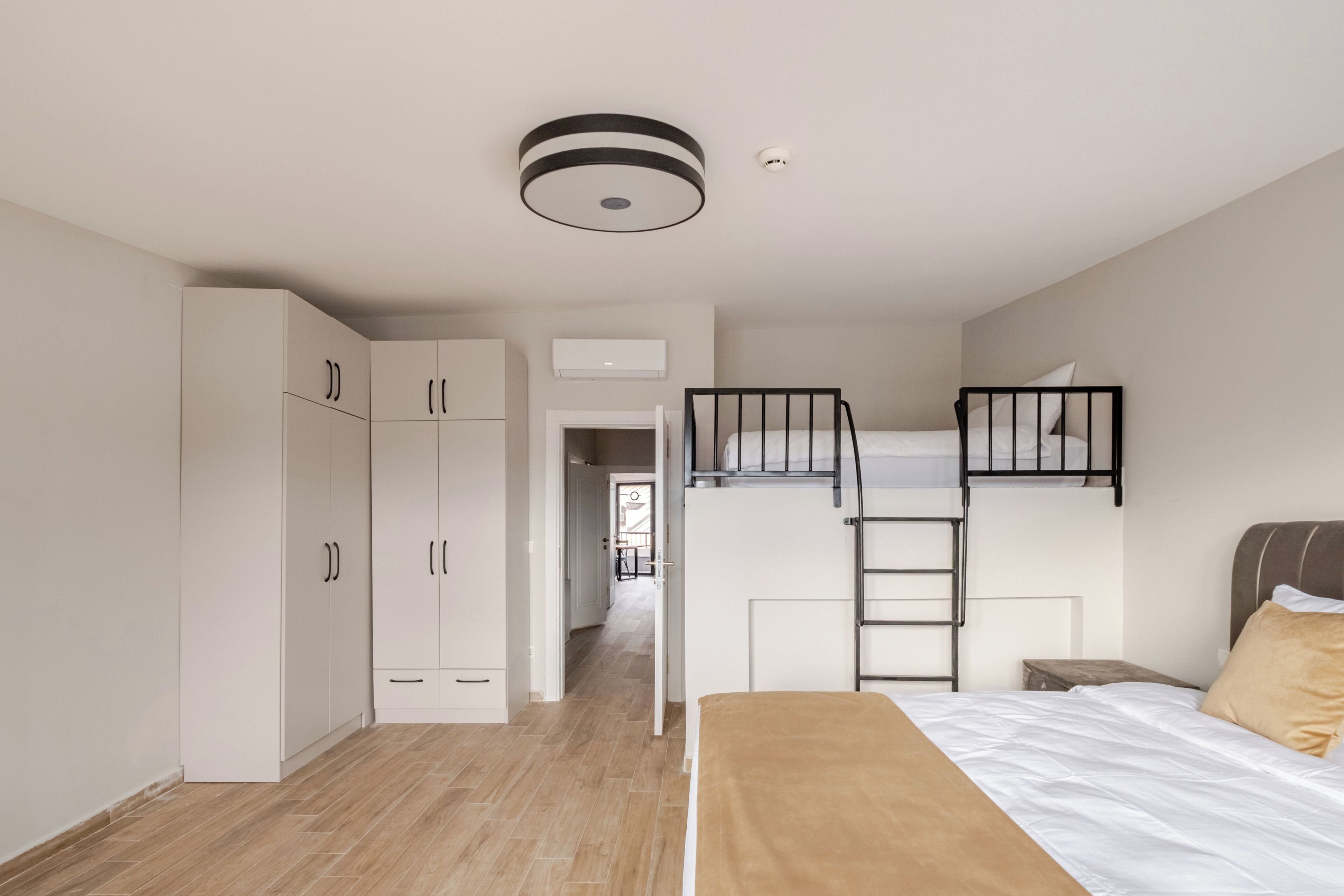 A bedroom with a bunk bed, a wardrobe, a desk, and a staircase.