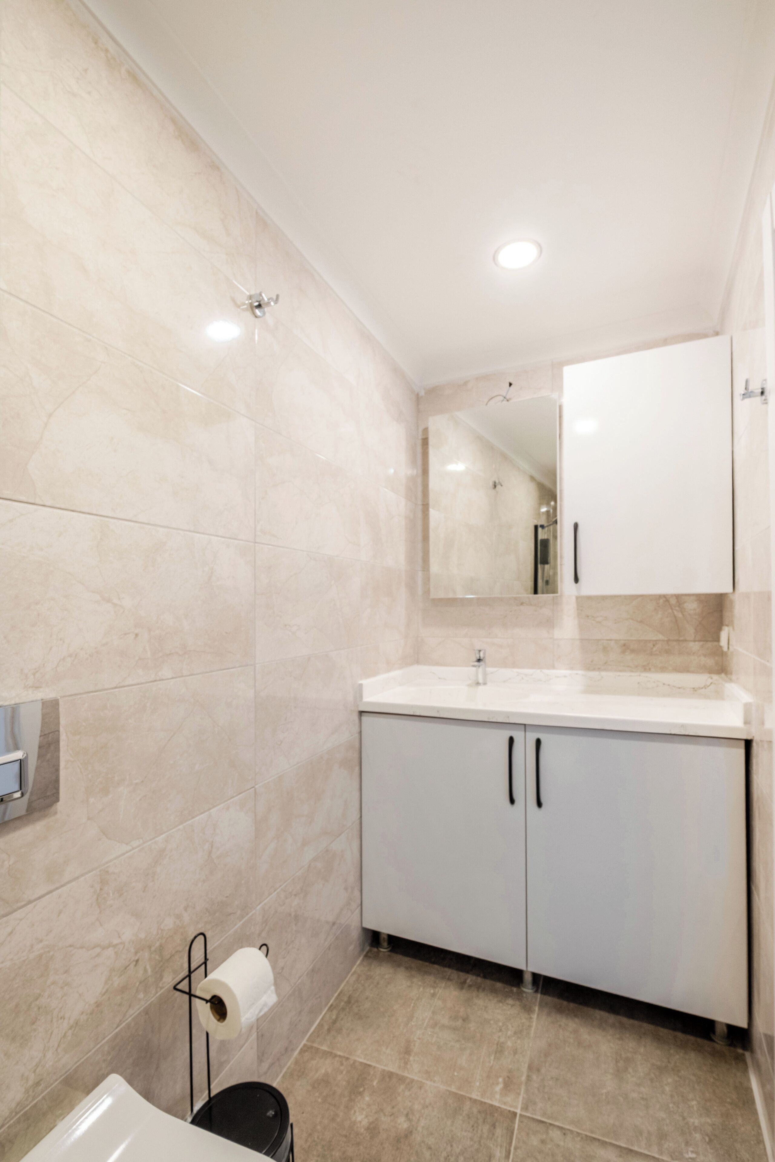 A modern bathroom with a marble floor, a white sink, and a mirror above the sink.