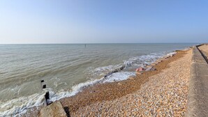 Ein Kiesstrand mit einer Betonpromenade entlang des Wassers.