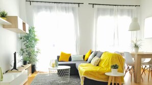 A modern living room with a sofa, a coffee table, and a dining area. - Malaga Refino Apartment With Rooftop Pool (Málaga)