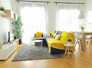 A modern living room with a sofa, a coffee table, and a dining area. - Malaga Refino Apartment With Rooftop Pool (Málaga)