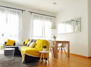 Ein modernes Wohnzimmer mit einer Couch, einem Esstisch und einem kleinen Beistelltisch.