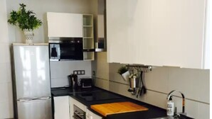 A compact kitchen with a refrigerator, microwave, oven, washing machine, and a sink. - Malaga Refino Apartment With Rooftop Pool (Málaga)