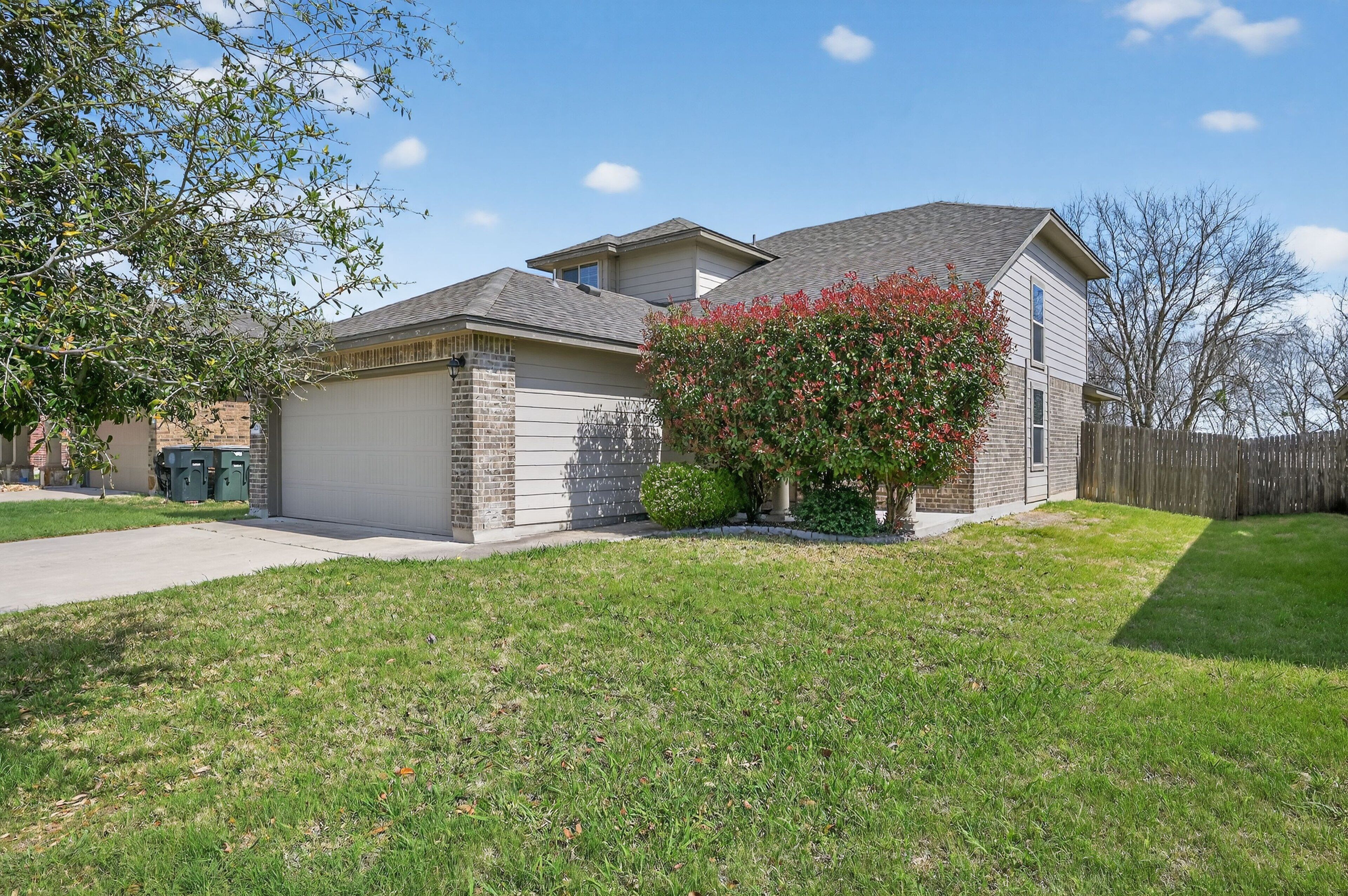 A two-story house with a garage, a small attached shed, and a well-maintained lawn.