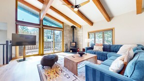 A spacious living room with a large blue sofa, a wooden coffee table, and a stone fireplace. - Chateau Sans Nom #35 4 Bedroom Condo (Mammoth Lakes)