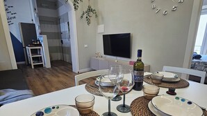 Ein Essbereich mit einem Tisch, gedeckt für vier Personen, einem an der Wand montierten Fernseher und einer dekorativen Uhr.