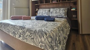 Ein Schlafzimmer mit Bett, Einbauschränken, einem Heizkörper und einer Wanddekoration.
