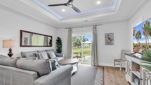 Ein modernes Wohnzimmer mit einer Couch, einem Couchtisch, einem Fernseher und Blick ins Freie.