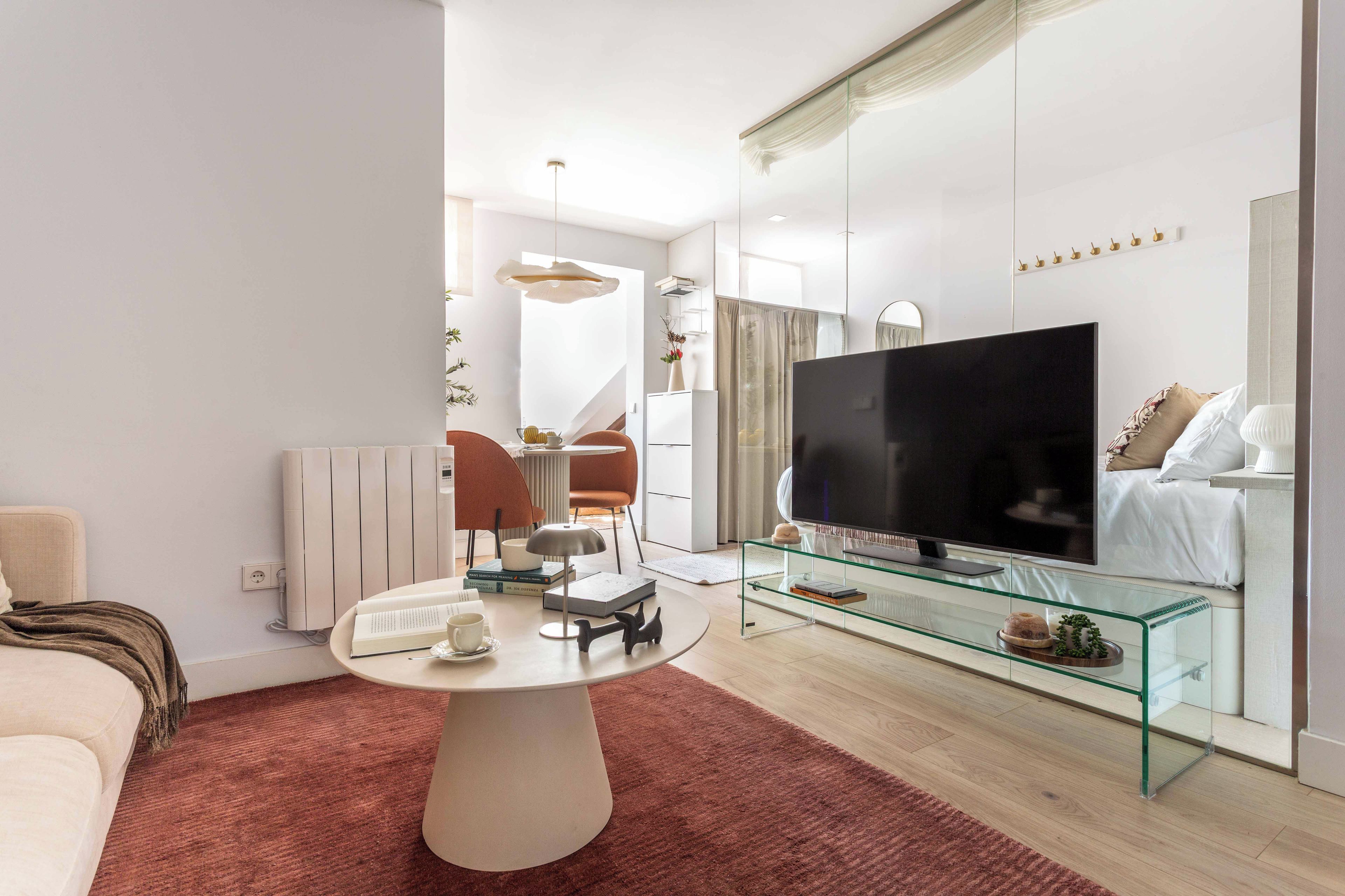 A modern living room with a flat-screen TV, a glass coffee table, and a sofa.