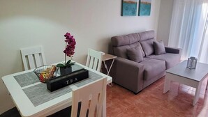 A living room with a sofa, a dining table with chairs, a yellow pendant light, and two wall-mounted paintings. - Cozy Apartment in Vera, Just Steps From the Beach (Vera)