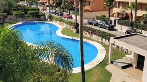 A swimming pool surrounded by palm trees and a residential area with buildings. - Cozy Apartment in Vera, Just Steps From the Beach (Vera)