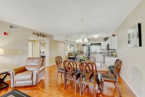 A dining area with a table and chairs, a kitchen in the background, and a living room with a sofa and a lamp. - Two bedroom, two bath condo| Near the Old Mill District| Dollywood| Sleeps 6 (Pigeon Forge)