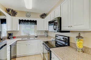 A kitchen with white cabinets, a black refrigerator, a stove, and a coffee maker. - Two bedroom, two bath condo| Near the Old Mill District| Dollywood| Sleeps 6 (Pigeon Forge)