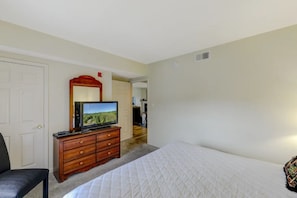 A bedroom with a bed, a dresser with a television, a chair, and a door. - Two Bedroom, Two bathroom Condo in Pigeon Forge| Near Dollywood| Sleeps 6 (Pigeon Forge)