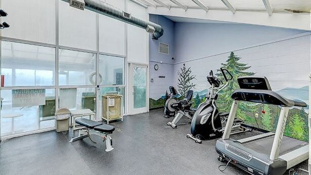 Een sportschool met trainingsapparatuur, een bank en een groot raam.