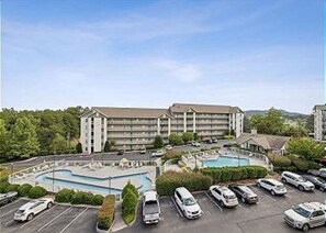 A hotel with a swimming pool, parking lot, and a large building with multiple floors. - Two Bedroom, Two bathroom Condo in Pigeon Forge| Near Dollywood| Sleeps 6 (Pigeon Forge)