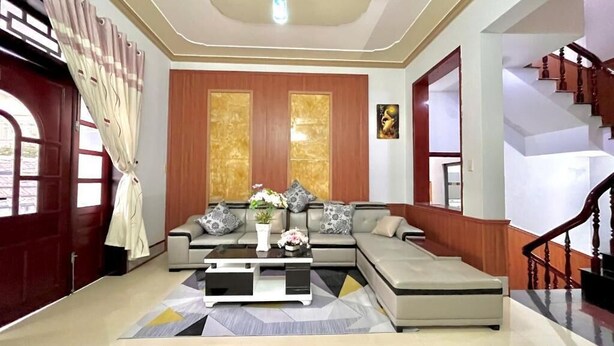 A modern living room with a sectional sofa, a coffee table, and a staircase. - Mekong INN (Can Tho)