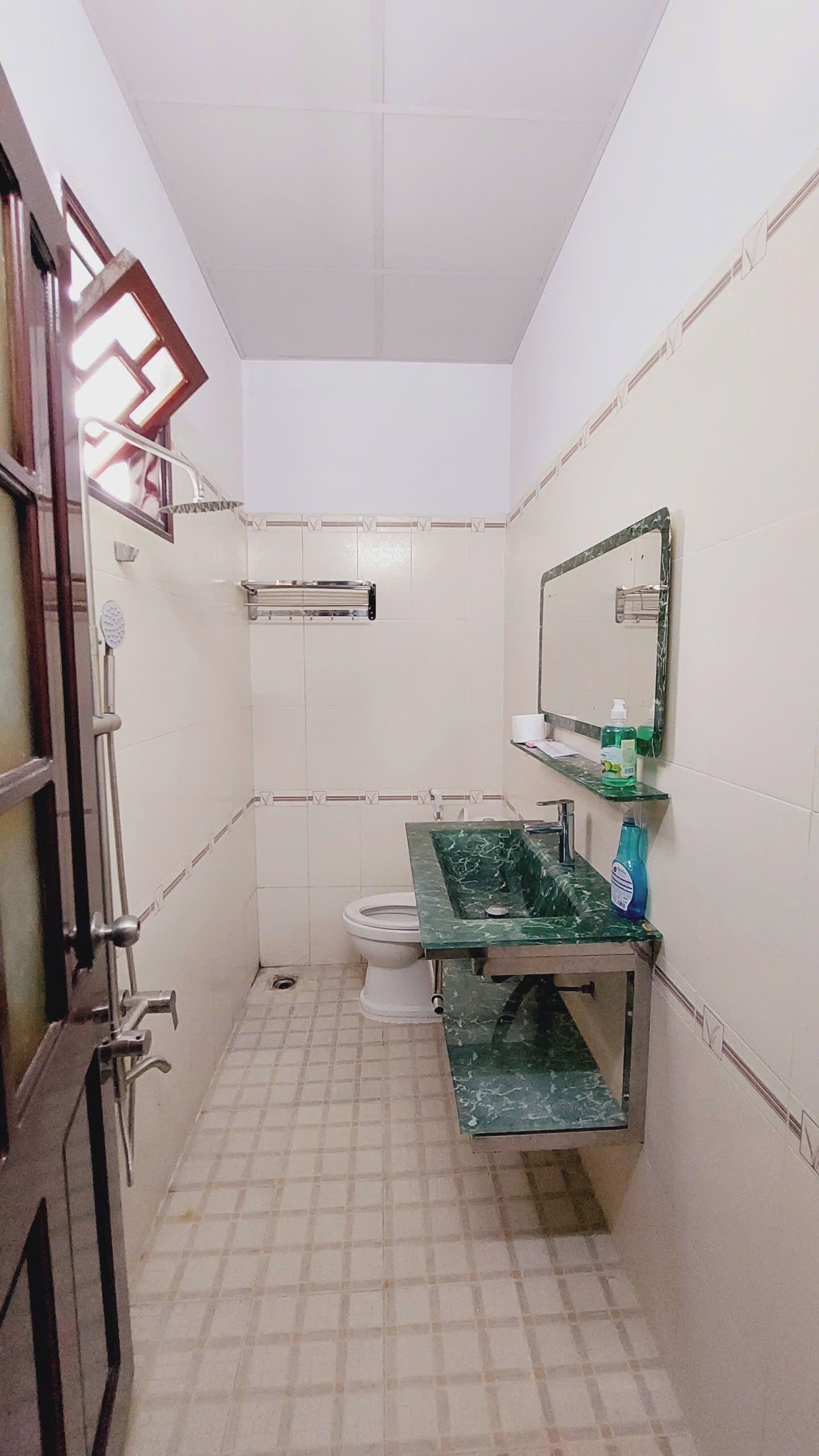 Une petite salle de bain comprenant des toilettes, un lavabo avec un plan de travail en marbre, un miroir et un espace douche.