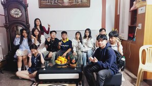 A group of people seated on a couch in a room with a clock and a framed picture on the wall. - Mekong INN (Can Tho)