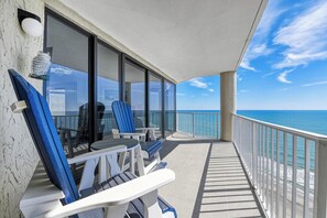 Een balkon met stoelen en een tafel, met uitzicht op zee.
