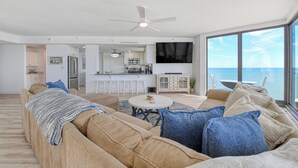 Ett modernt vardagsrum med en soffa, ett soffbord och utsikt över havet.