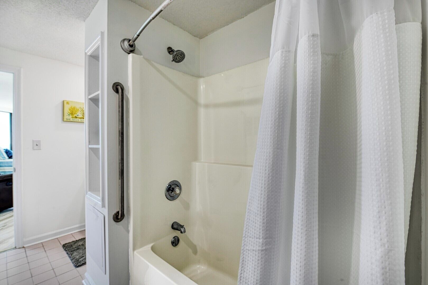 A bathroom with a bathtub, a shower with a handheld showerhead, and a white shower curtain.