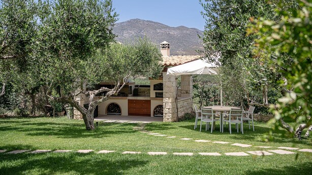 A stone house with a tiled roof, surrounded by a well-maintained garden and olive trees, with a mountain in the background. - Stunning Mediterranean Villa for 6 (Kissamos)