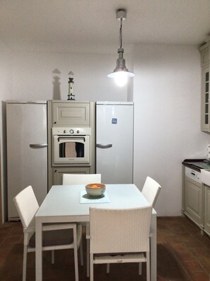 Una cocina pequeña con electrodomésticos blancos, una mesa de comedor y sillas.