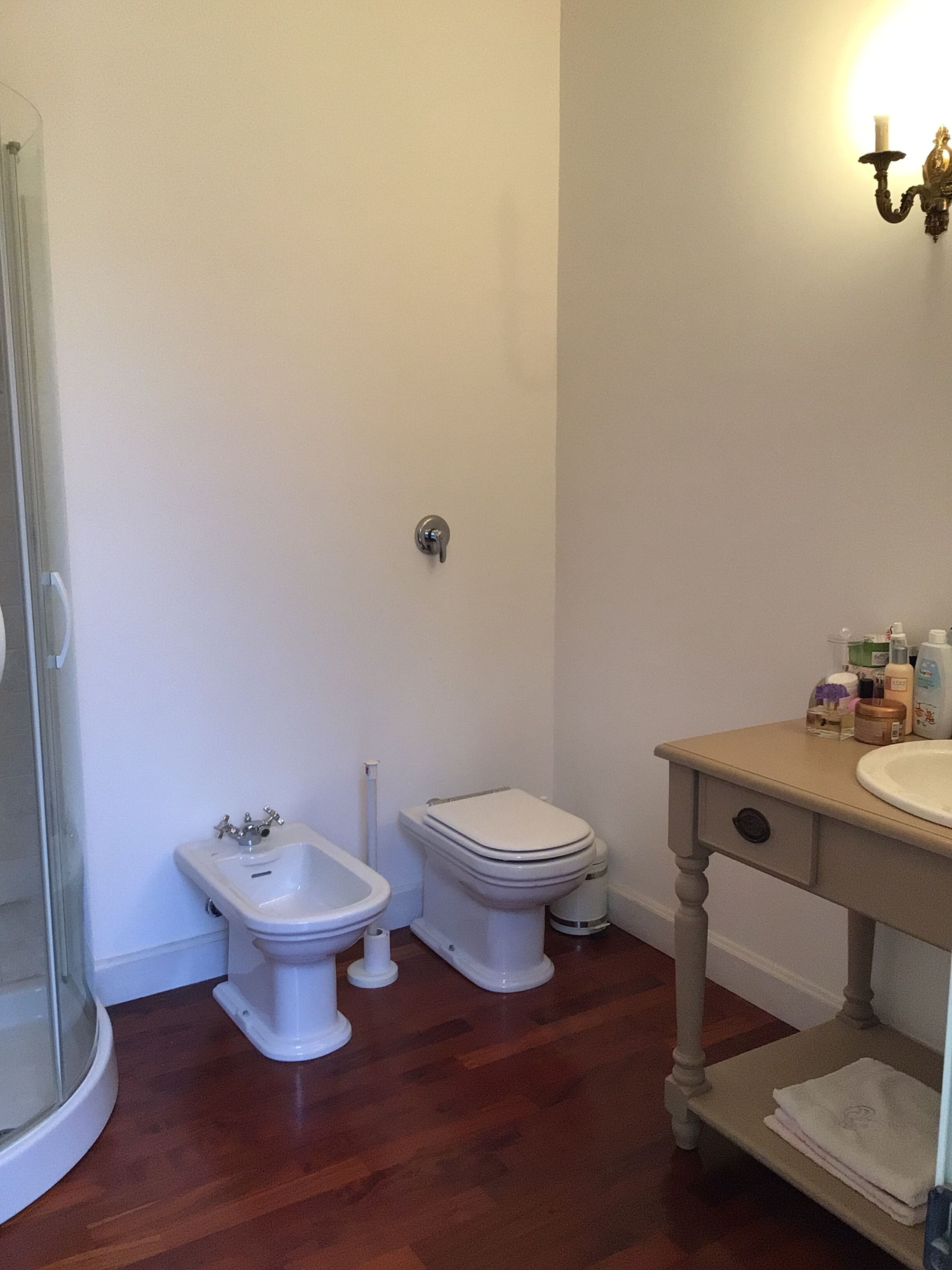 Ein Badezimmer mit Bidet, Toilette, Waschbecken und einer Duschkabine aus Glas.