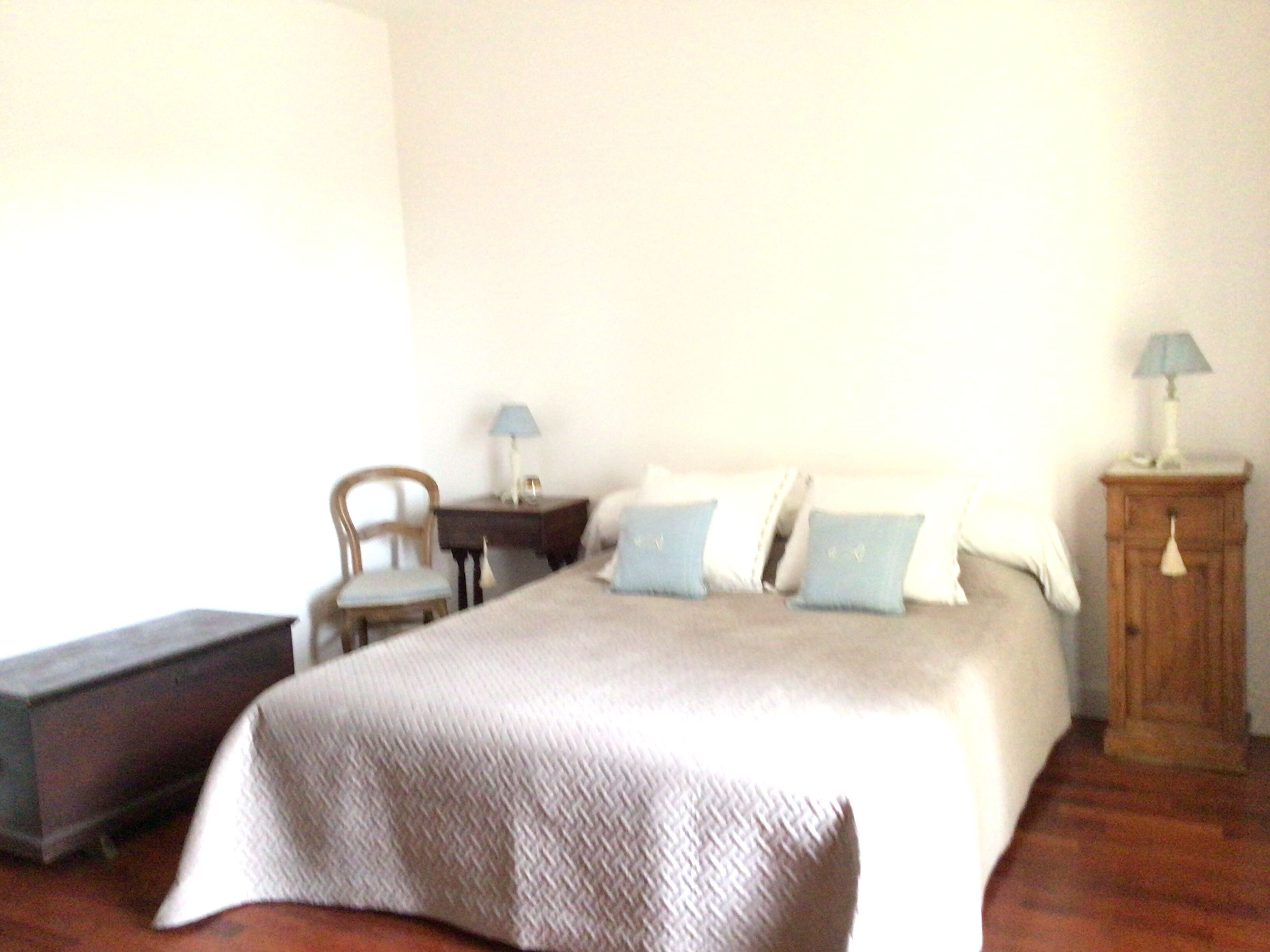 Une chambre à coucher avec un lit, une chaise, une table de chevet et une lampe.