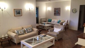 Una sala de estar con sofá, sillón, mesa de centro y un cuadro en la pared.