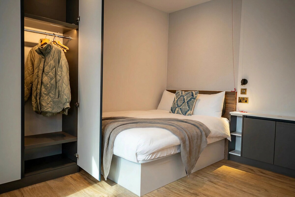 A bedroom with a bed, a wardrobe, and a bedside table.
