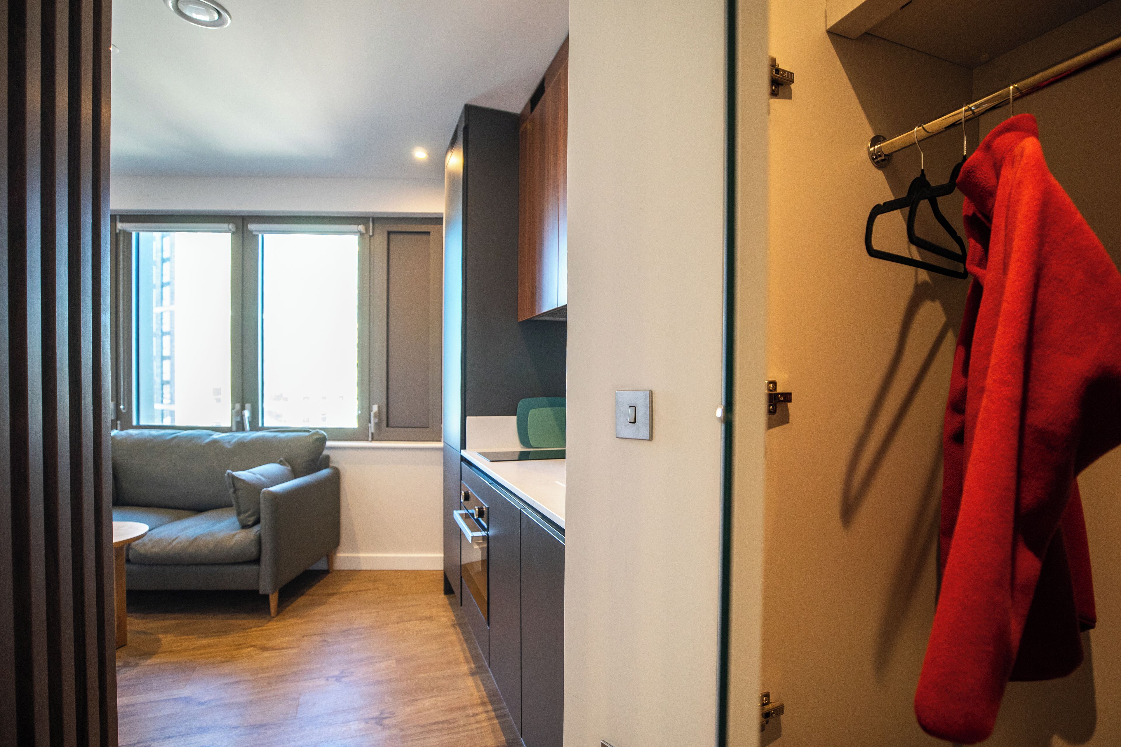 Ein modernes Interieur mit einer Couch, Holzböden, einer Küchenzeile und einem roten Handtuch an einem Haken.