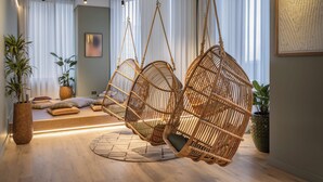 A modern interior with a hanging rattan chair, a bed with pillows, and a potted plant. - StayCozy Studio Apartments in Acton (London)