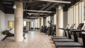 A gym with exercise equipment, treadmills, and a concrete pillar. - StayCozy Studio Apartments in Acton (London)