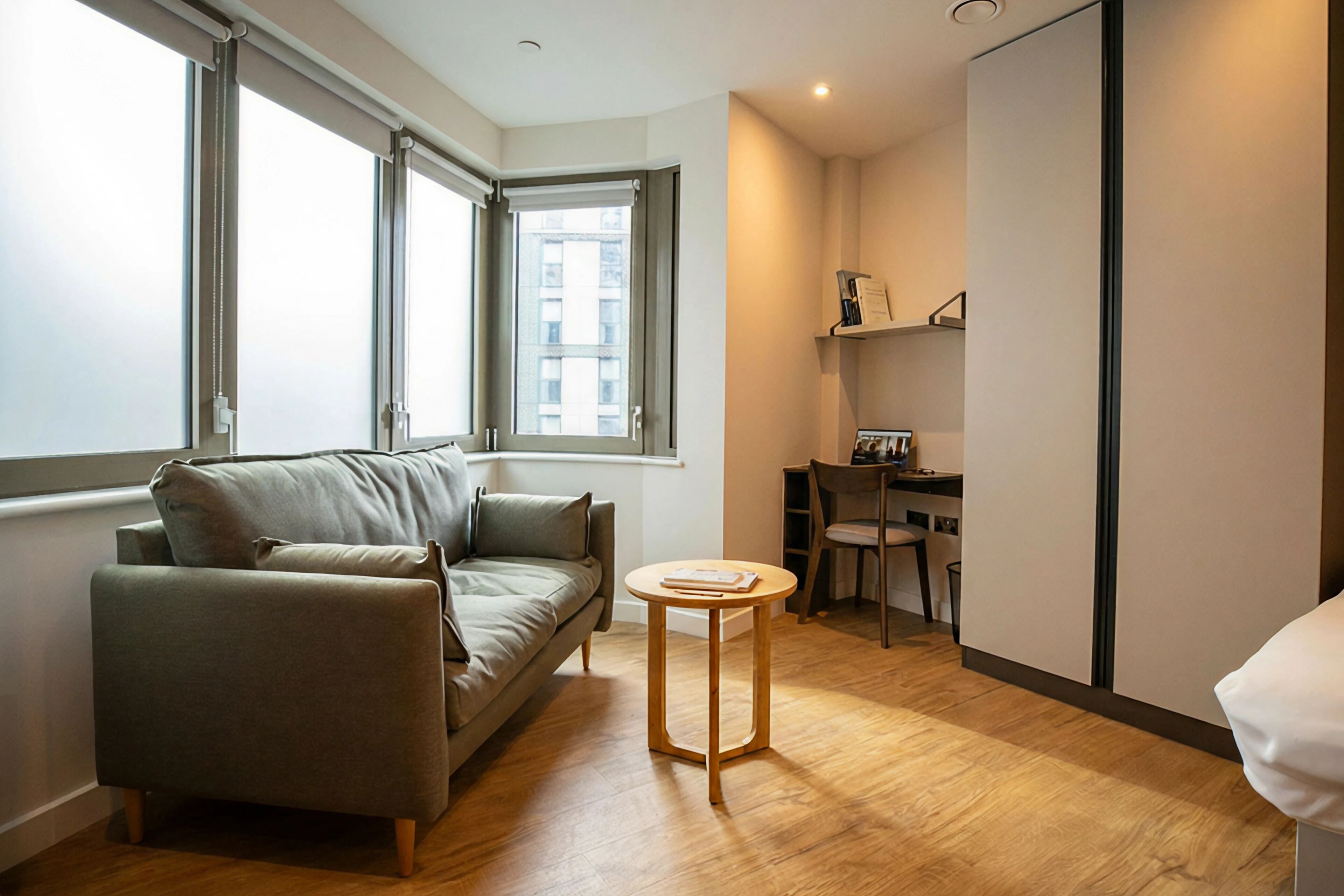 Een moderne woonkamer met een bank, een kleine ronde tafel en een bureau met stoel.